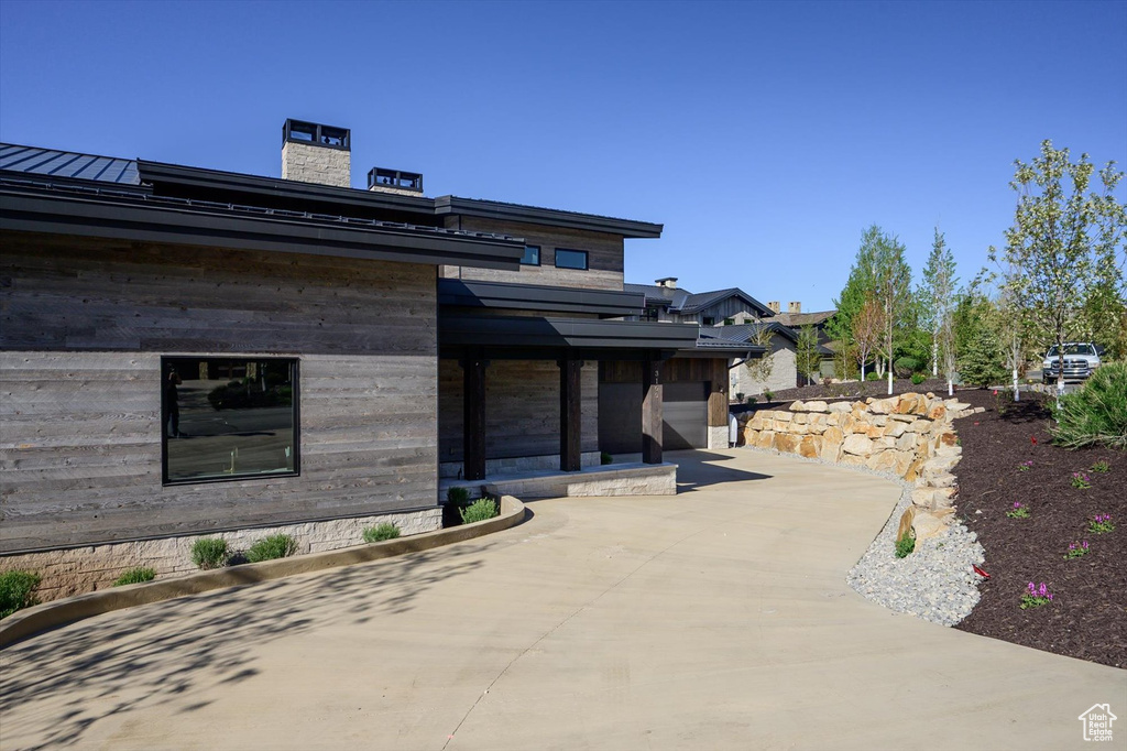 View of front of house featuring a standing seam roof, a chimney, and metal roof
