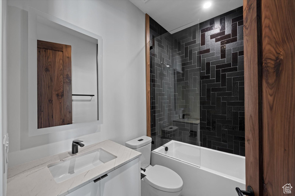 Full bathroom featuring tiled shower / bath combo, vanity, and toilet