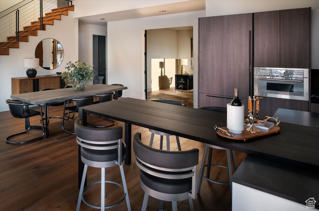 Interior space with dark wood-type flooring, oven, and dark brown cabinets