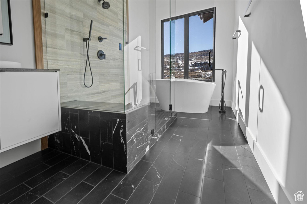 Bathroom featuring tile flooring and shower with separate bathtub