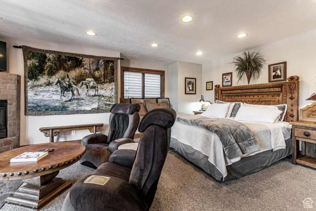 Bedroom featuring a stone fireplace, a textured ceiling, and carpet