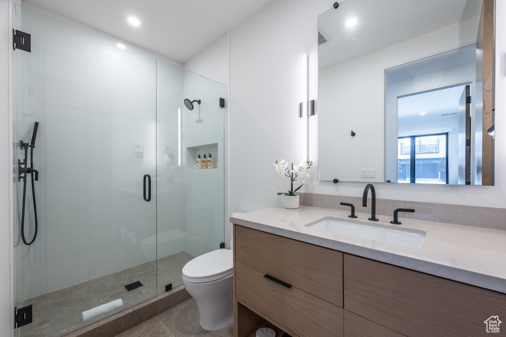 Bathroom with vanity, an enclosed shower, and toilet