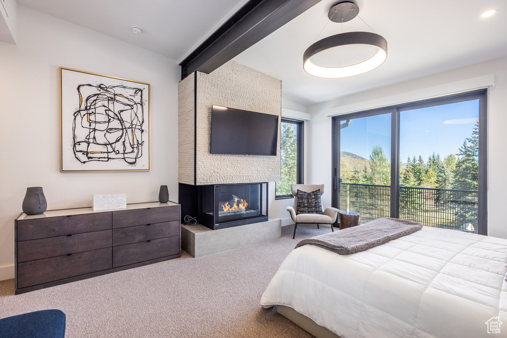 Bedroom with a multi sided fireplace, beam ceiling, and carpet