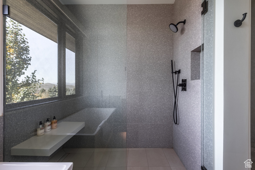 Bathroom with tile patterned floors and tiled shower