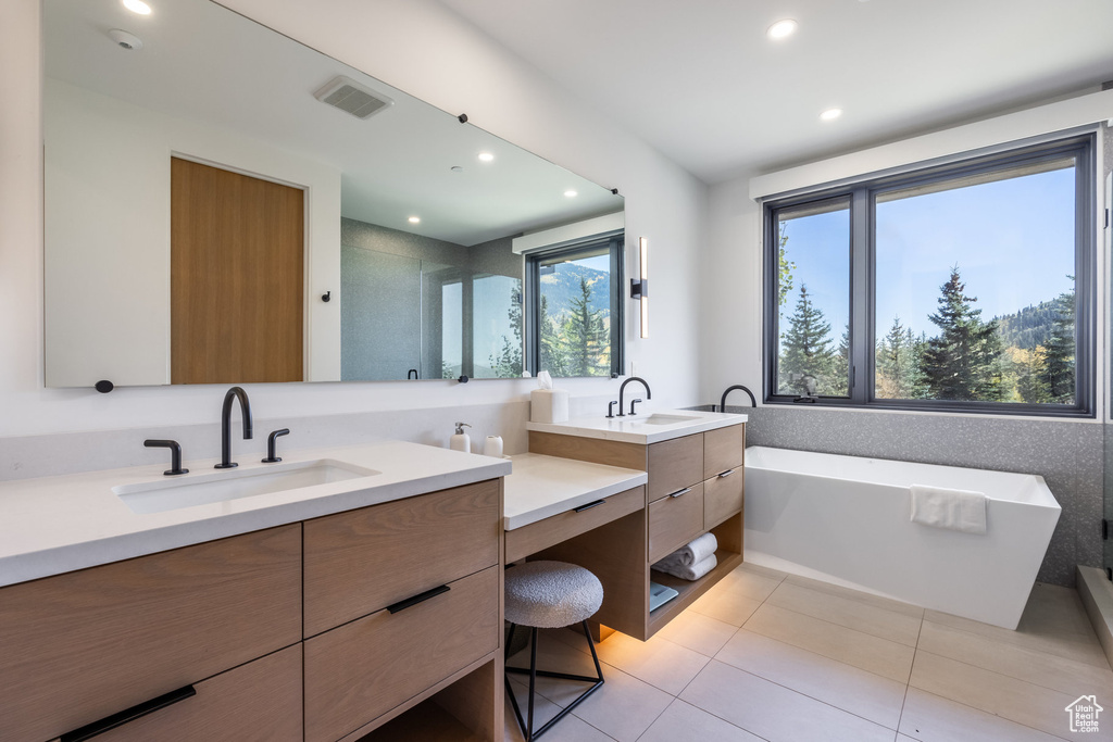 Bathroom featuring a tub to relax in, tile patterned floors, and vanity