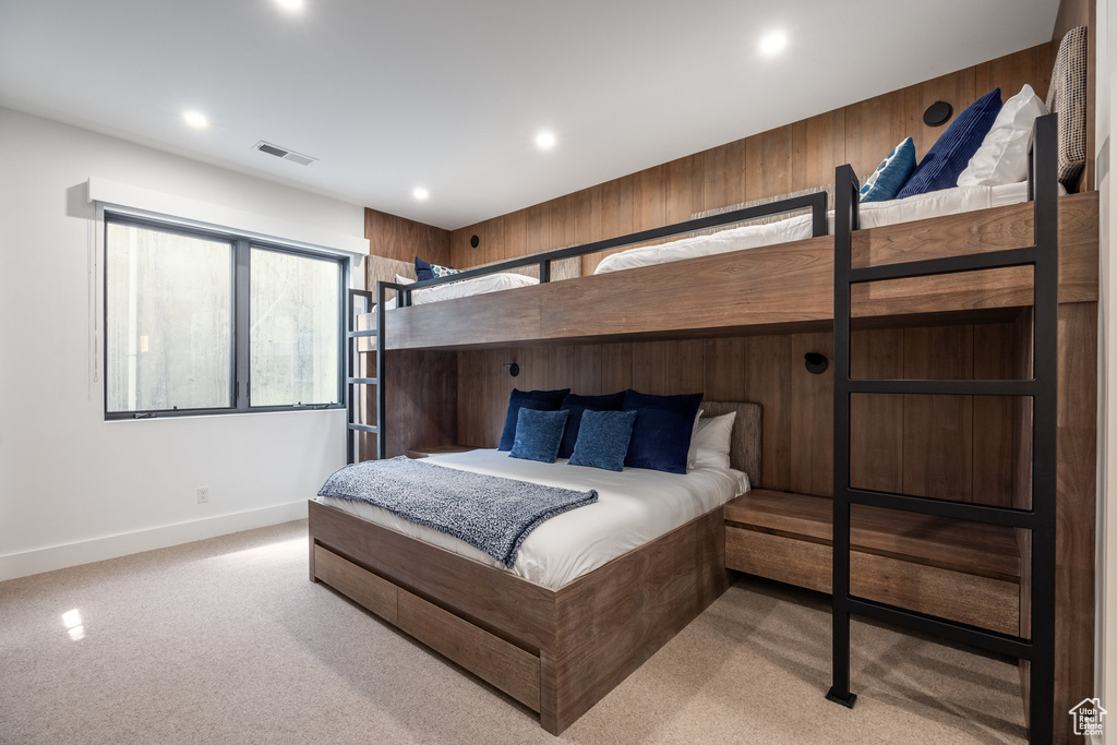 Bedroom with light colored carpet and wooden walls