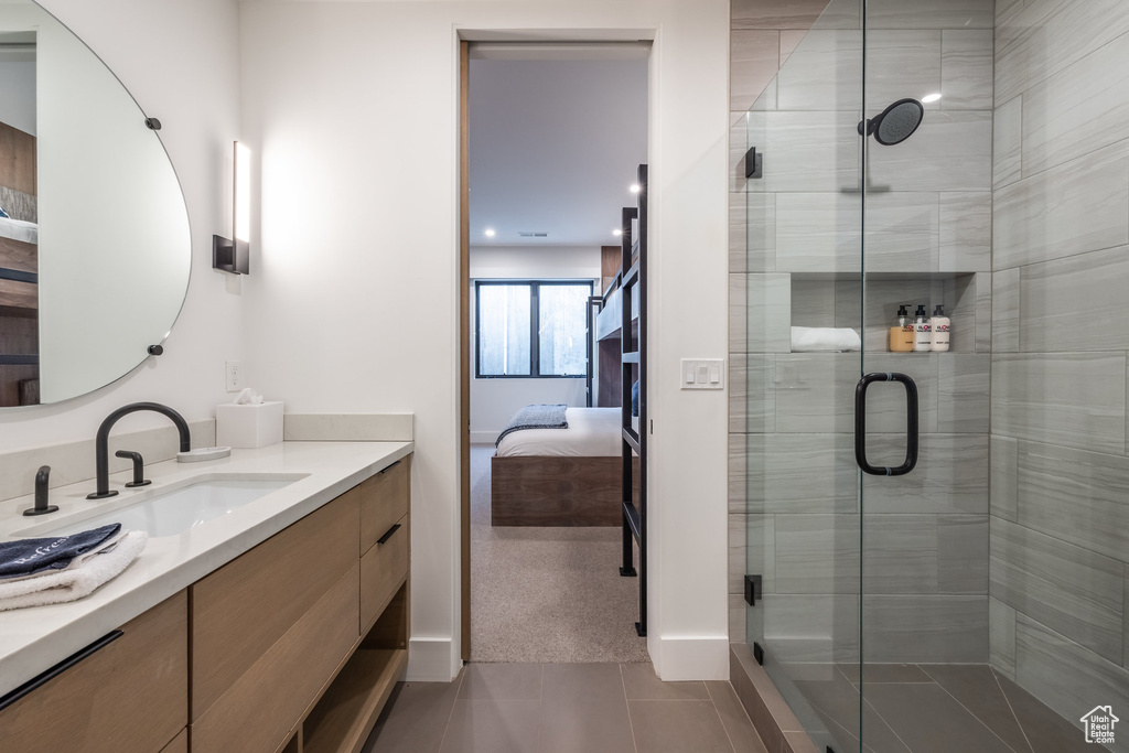 Bathroom with tile patterned floors, a shower with door, and vanity