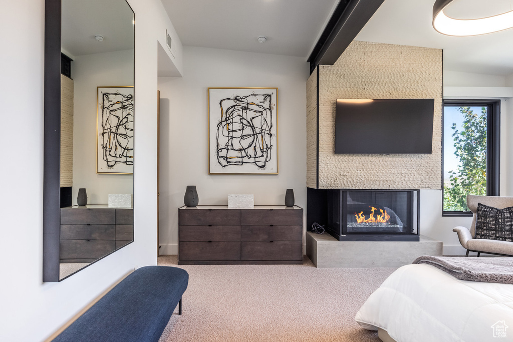 Bedroom with a multi sided fireplace, carpet, and beamed ceiling