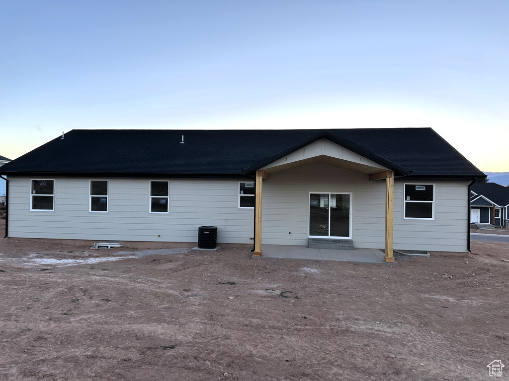 Back house at dusk with a patio and central AC unit