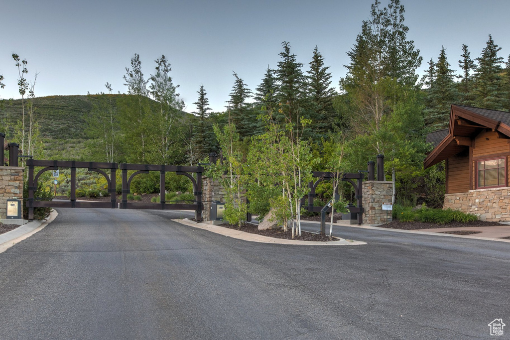 View of asphalt road with a gate, a gated entry, a mountain view, and curbs