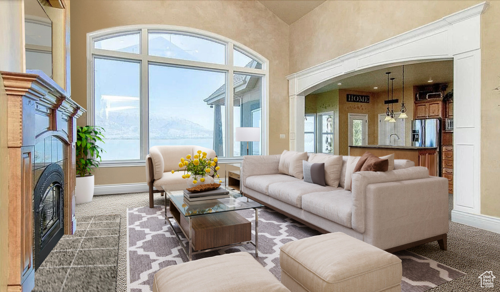 Carpeted living room with a towering ceiling, sink, and a tile fireplace