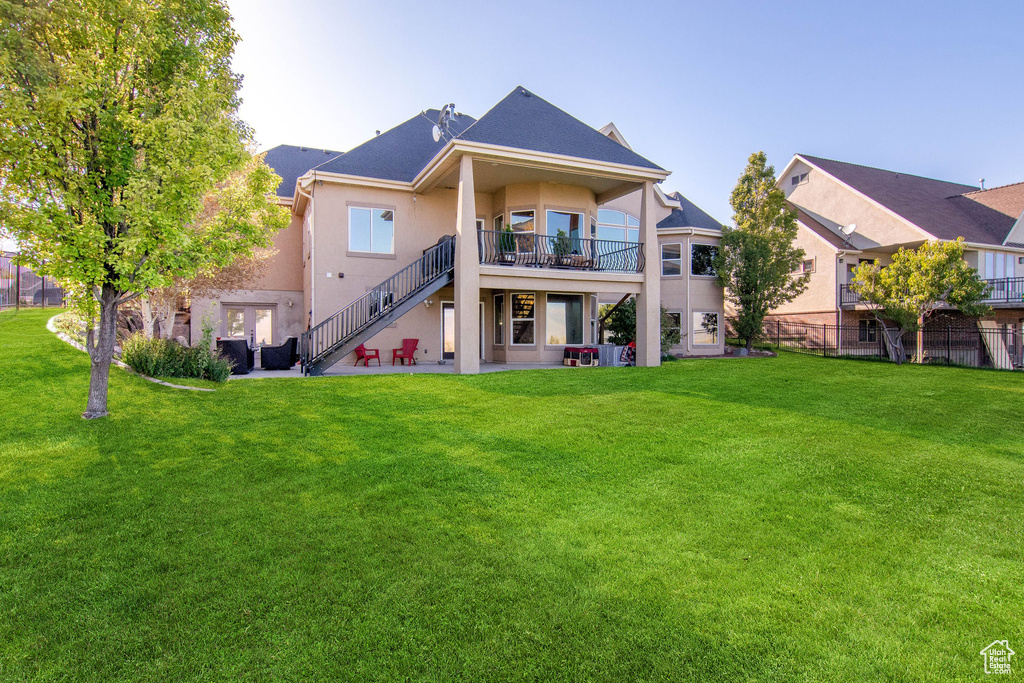 Back of property with central AC unit, a yard, and a patio