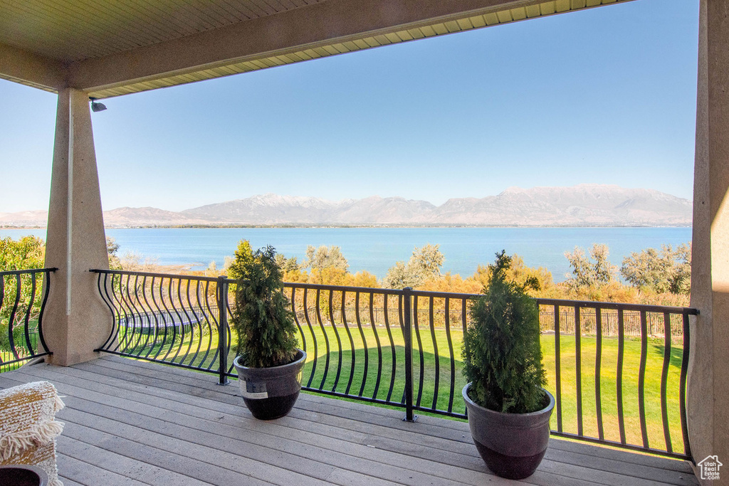 Wooden deck with a water and mountain view and a yard