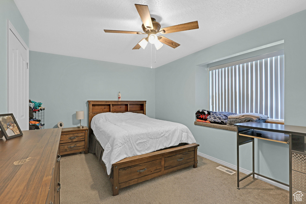 Carpeted bedroom featuring a textured ceiling and ceiling fan