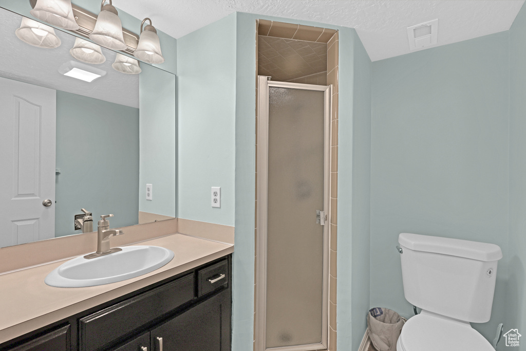 Bathroom with walk in shower, vanity, toilet, and a textured ceiling