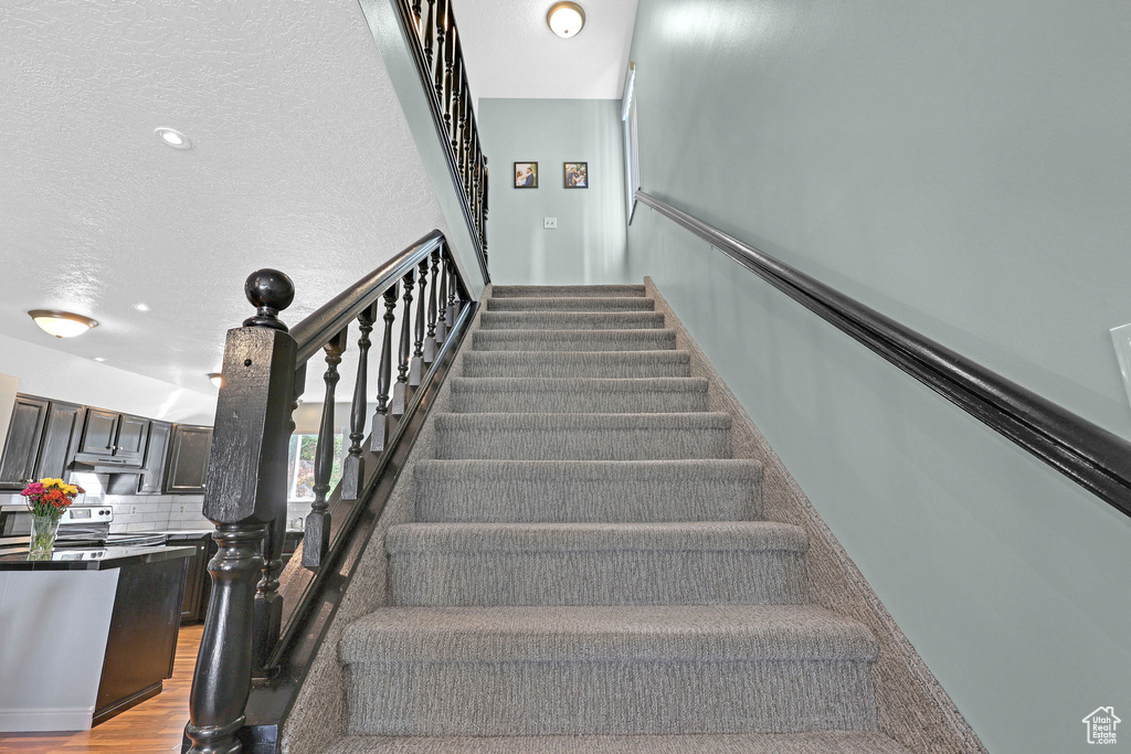 Stairs featuring a textured ceiling and hardwood / wood-style flooring