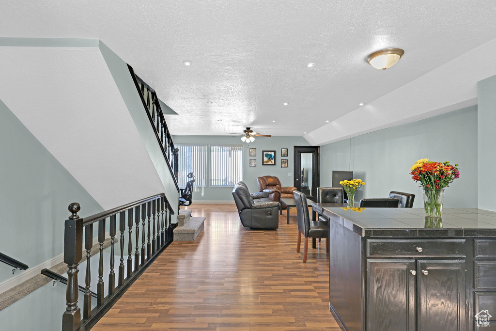 Interior space featuring a textured ceiling, lofted ceiling, dark hardwood / wood-style floors, and ceiling fan