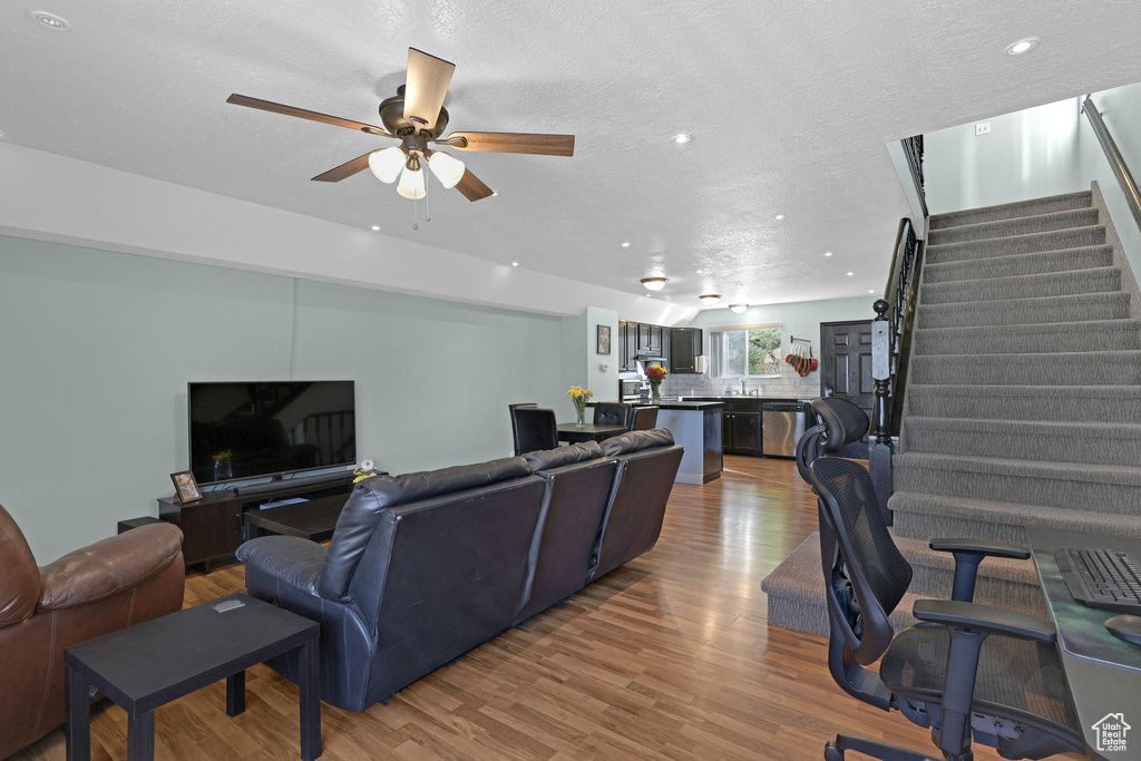 Living room featuring ceiling fan, a textured ceiling, and hardwood / wood-style floors