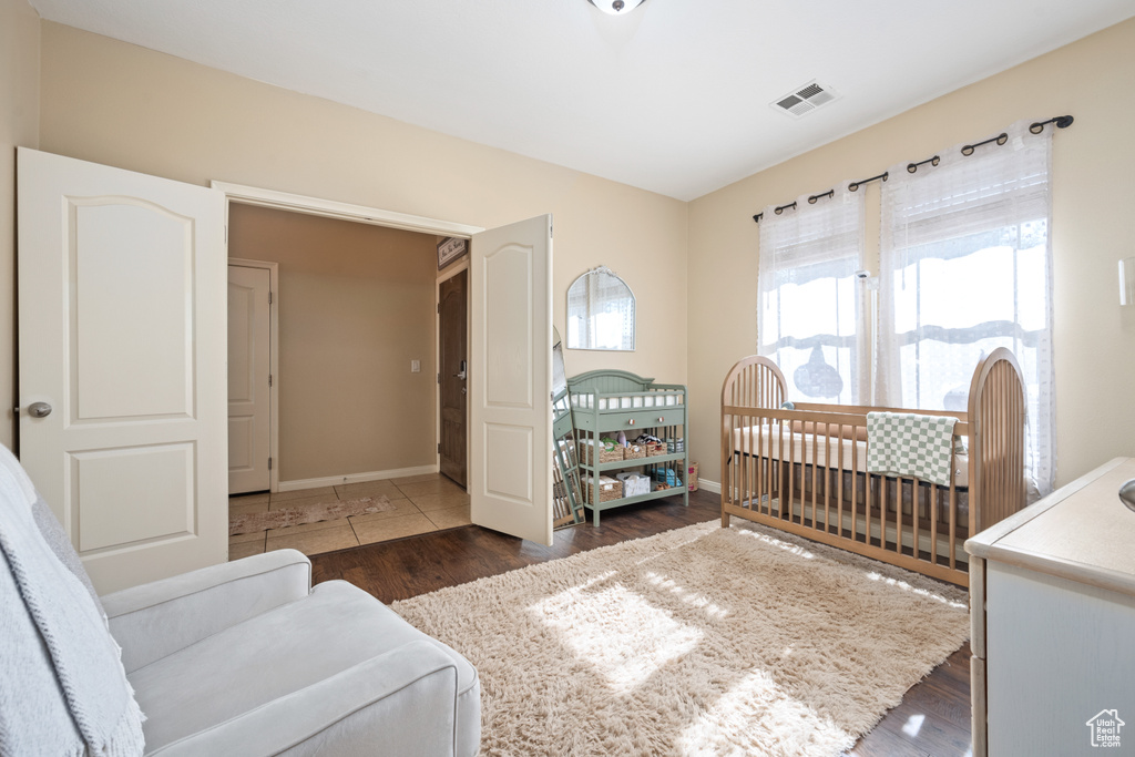 Bedroom with a nursery area and dark hardwood / wood-style flooring