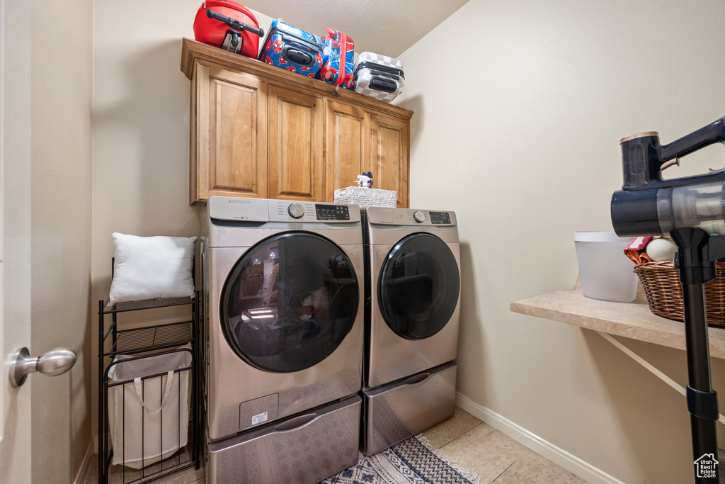 Laundry area with cabinets, light tile patterned floors, and washing machine and dryer