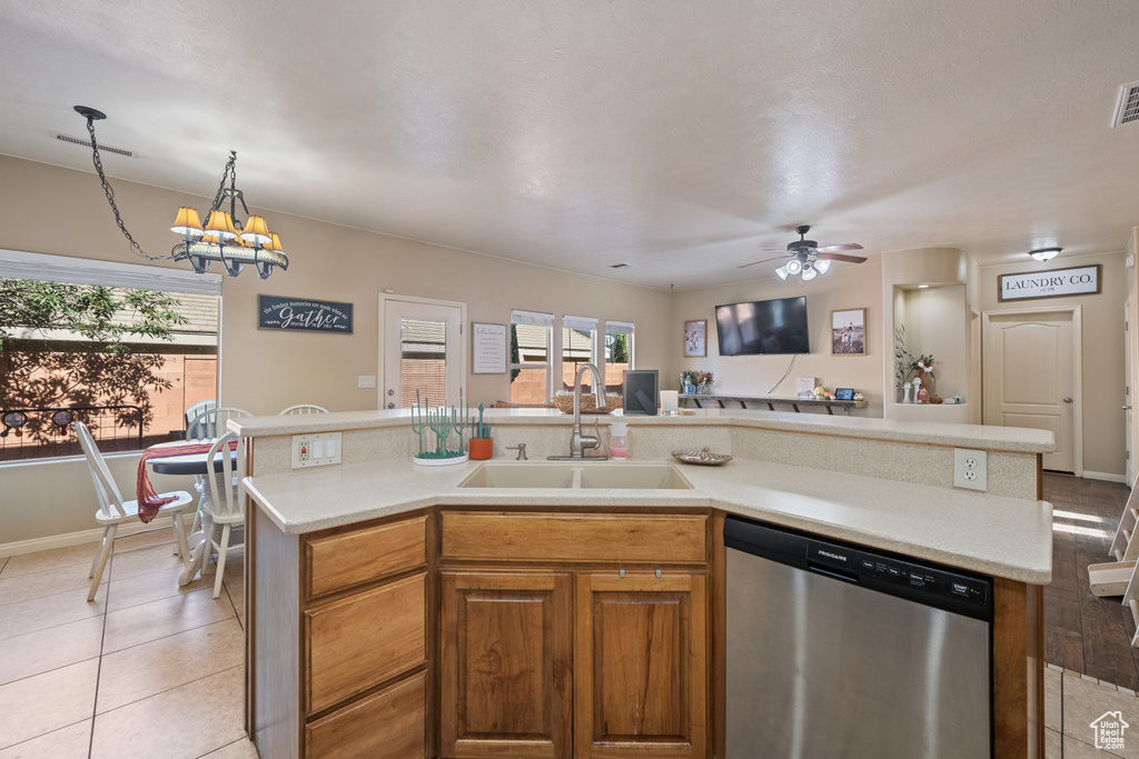 Kitchen with a center island with sink, sink, light tile patterned flooring, and stainless steel dishwasher