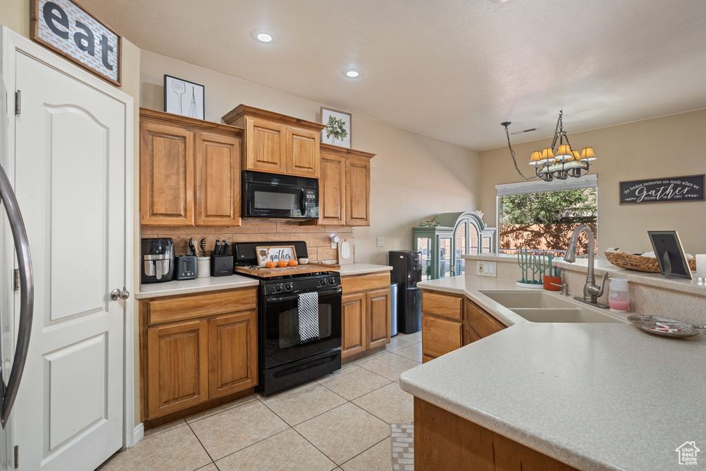 Kitchen featuring light tile patterned flooring, sink, hanging light fixtures, an inviting chandelier, and black appliances