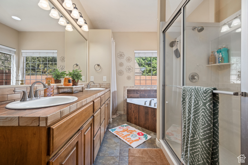 Bathroom featuring vanity, tile patterned flooring, and separate shower and tub