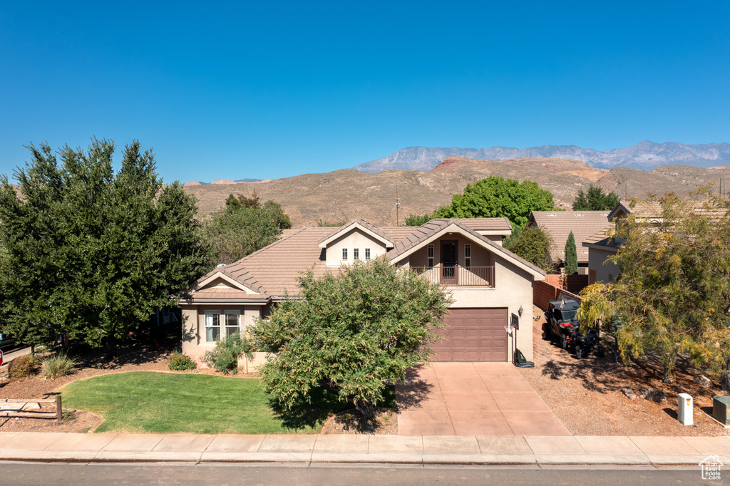 View of front of home featuring a mountain view, a front lawn, and a garage