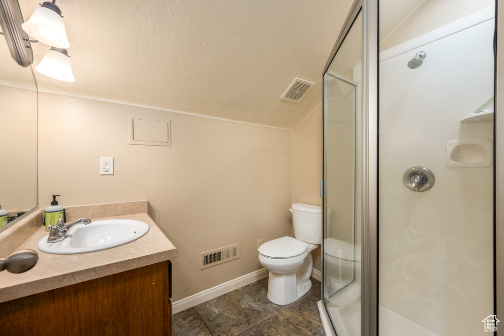 Bathroom featuring vanity, walk in shower, a textured ceiling, lofted ceiling, and toilet