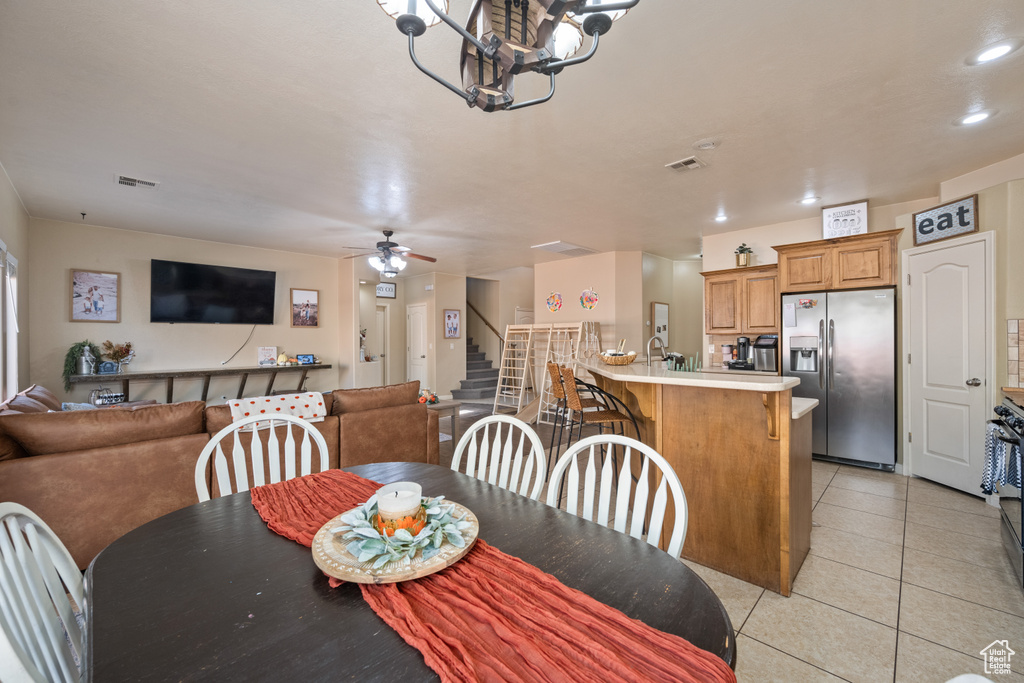 Tiled dining room featuring ceiling fan with notable chandelier and sink