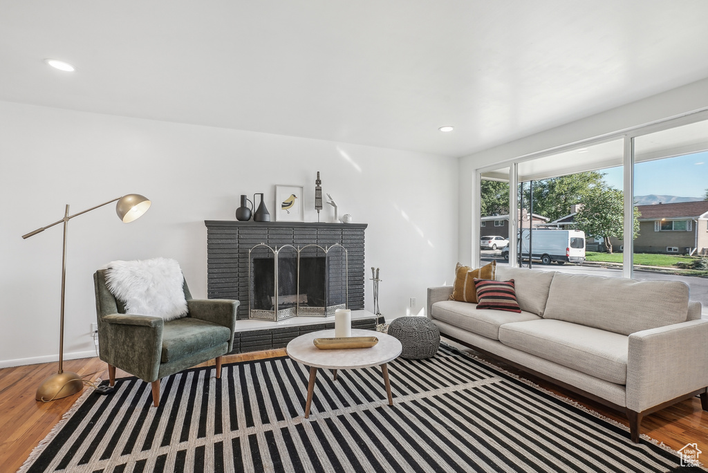 Living room with a brick fireplace and hardwood / wood-style flooring