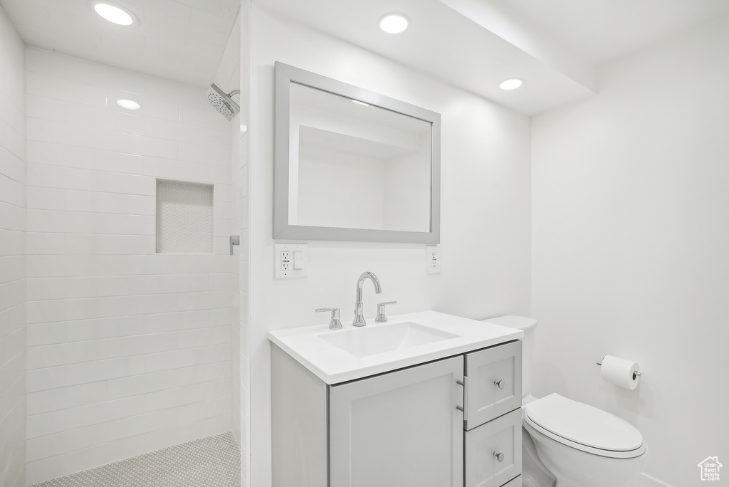 Bathroom featuring vanity, toilet, and tiled shower