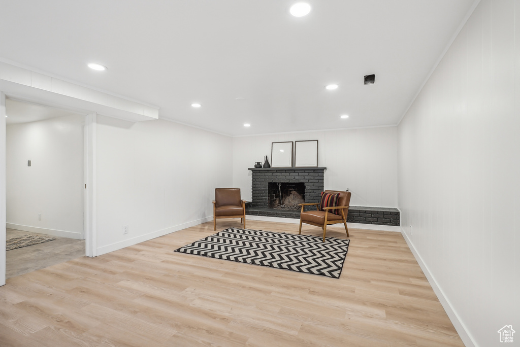 Living area with ornamental molding, light hardwood / wood-style floors, and a fireplace