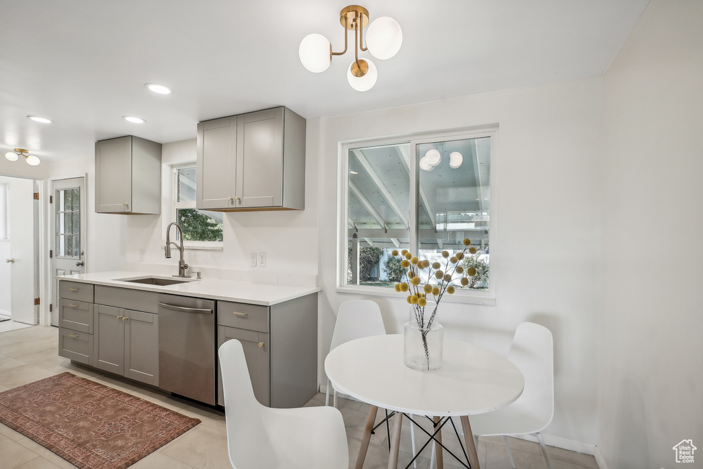 Kitchen with pendant lighting, sink, gray cabinetry, light tile patterned floors, and stainless steel dishwasher