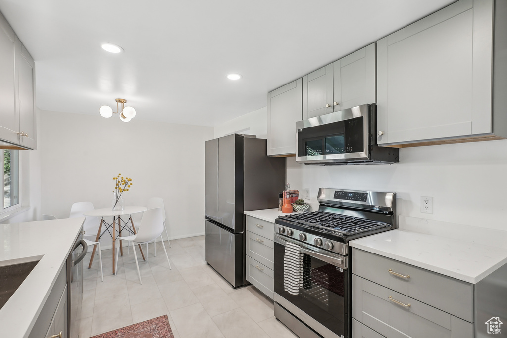 Kitchen featuring appliances with stainless steel finishes, light tile patterned floors, and gray cabinetry