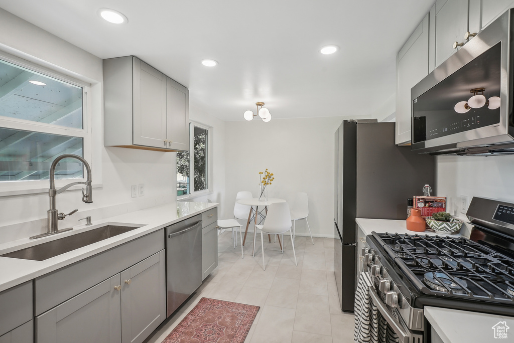 Kitchen with gray cabinetry, light tile patterned flooring, sink, and stainless steel appliances