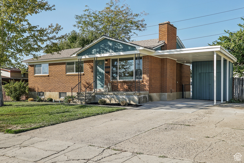 View of front facade featuring a front yard and a carport