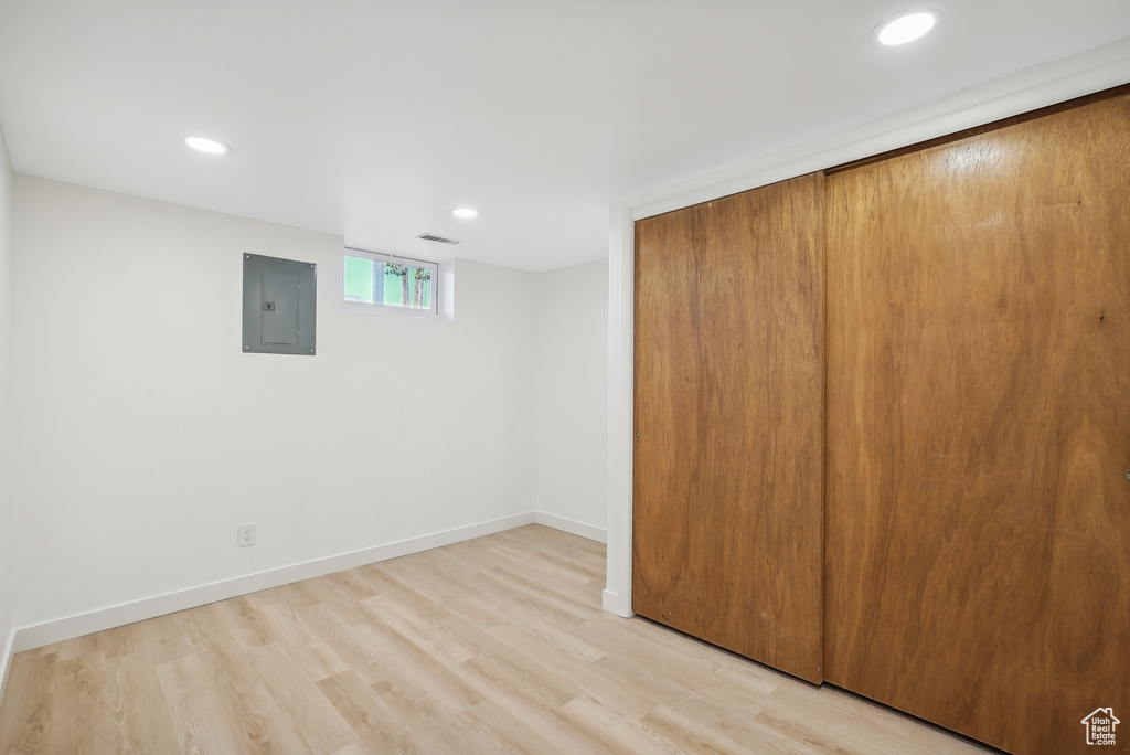 Basement featuring electric panel and light hardwood / wood-style floors