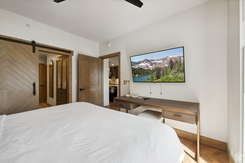 Bedroom featuring wood-type flooring, ceiling fan, and a barn door