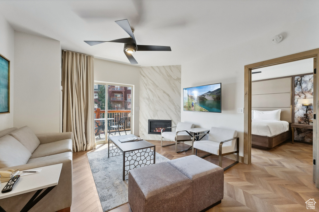 Living room featuring a premium fireplace, light parquet flooring, and ceiling fan