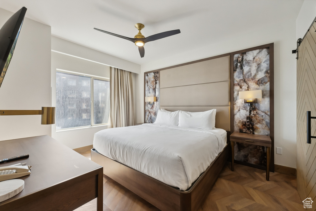 Bedroom featuring ceiling fan, parquet floors, and a barn door