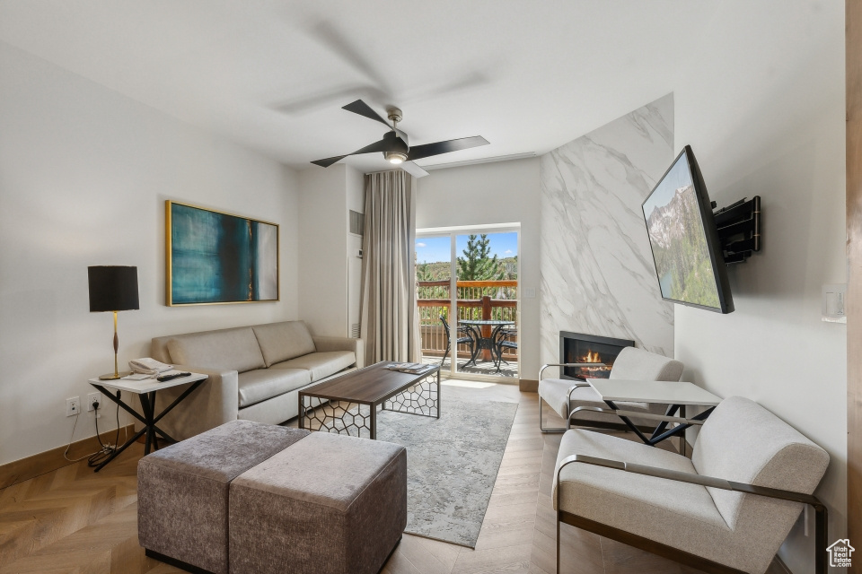 Living room featuring ceiling fan, a premium fireplace, and light parquet flooring