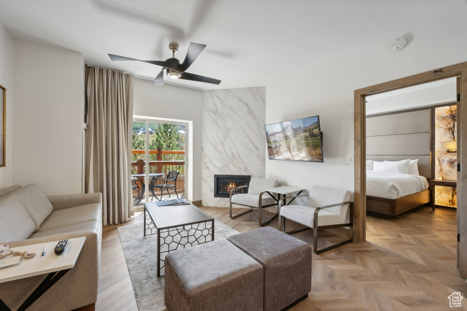 Living room featuring light parquet floors, ceiling fan, and a premium fireplace