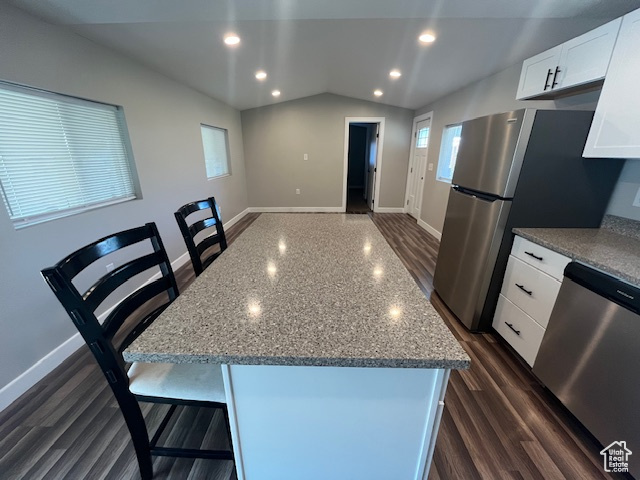 Kitchen with vaulted ceiling, white cabinets, a kitchen island, stainless steel appliances, and dark hardwood / wood-style floors