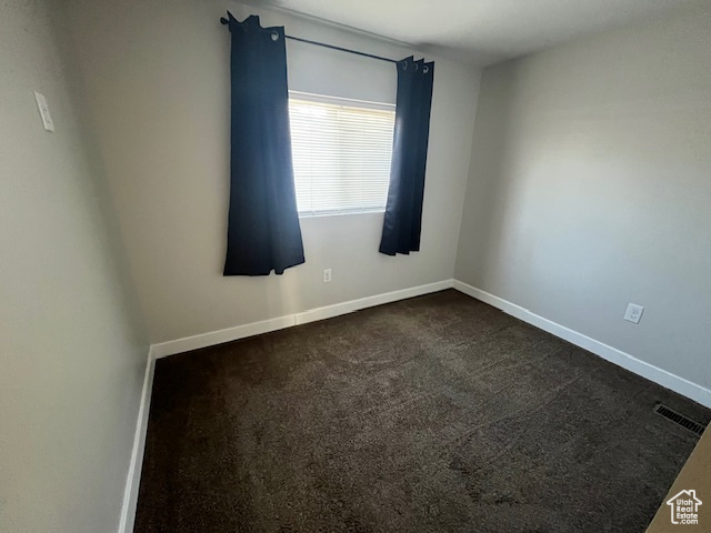 Spare room featuring dark colored carpet