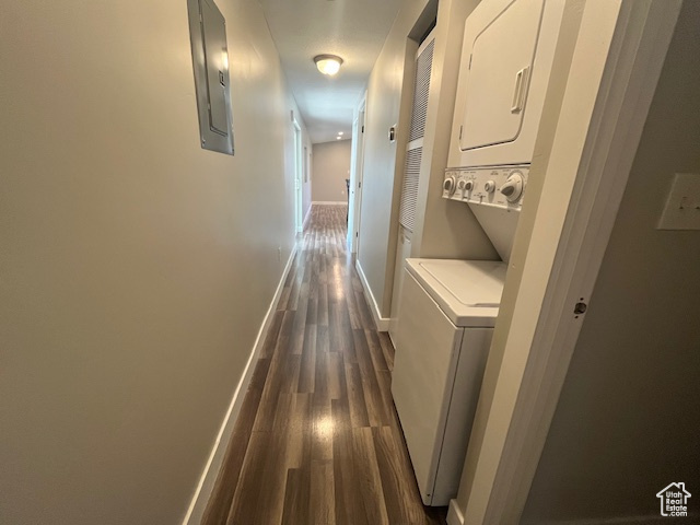 Laundry room with stacked washer and dryer, dark hardwood / wood-style flooring, and electric panel