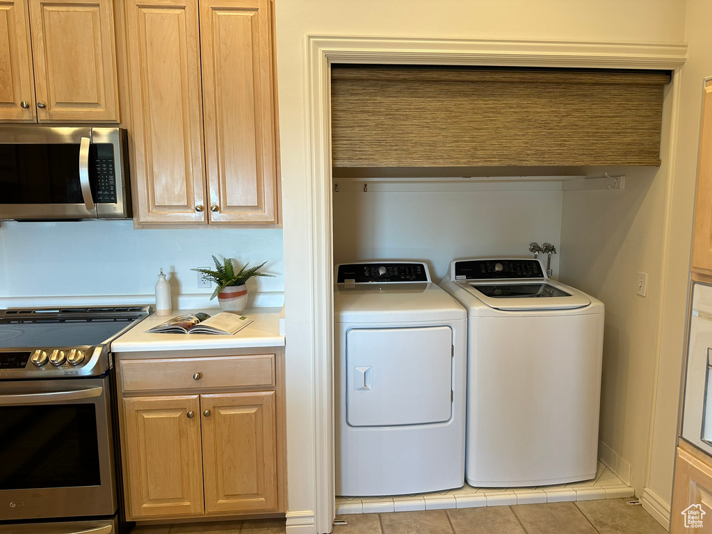 Laundry room featuring light tile patterned floors and washing machine and dryer