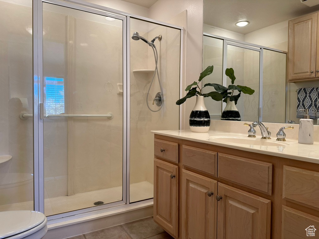 Bathroom featuring a shower with door, toilet, vanity, and tile patterned floors