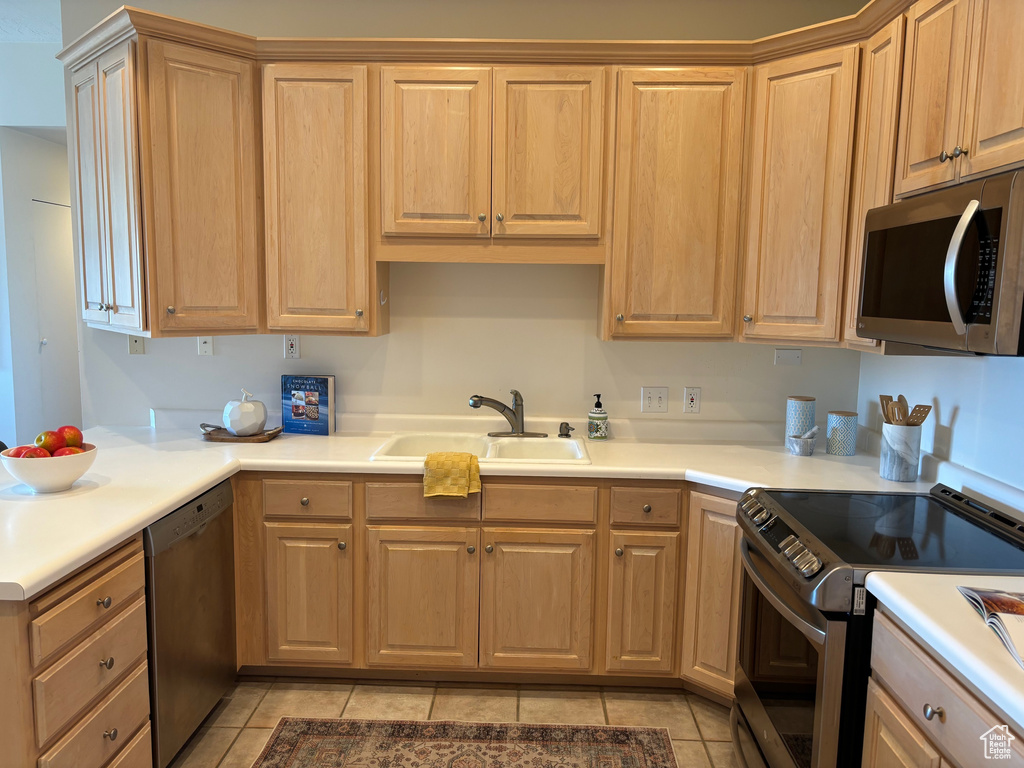 Kitchen with stainless steel appliances, light tile patterned flooring, and sink