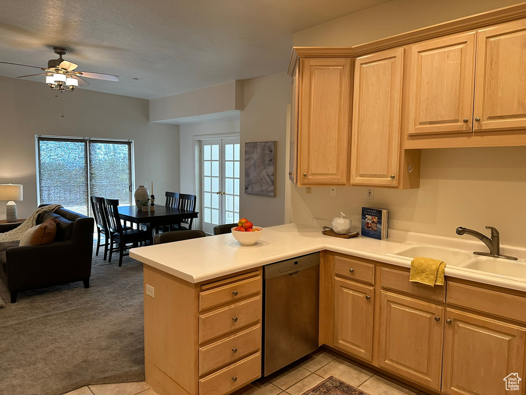 Kitchen with kitchen peninsula, ceiling fan, stainless steel dishwasher, sink, and light carpet